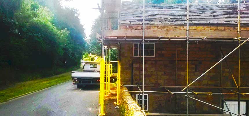 close up side view of simple builders scaffolding erected around a rural country house