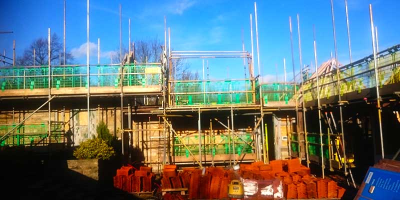 a very large scale building site with part buildings surrounded by high scaffolding supporting builders working