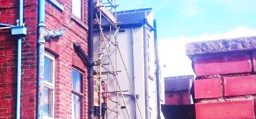 a terraced house with an erected scaffolding tower at the property rear to facilitate a safe esily accessible working environment for tradesmen
