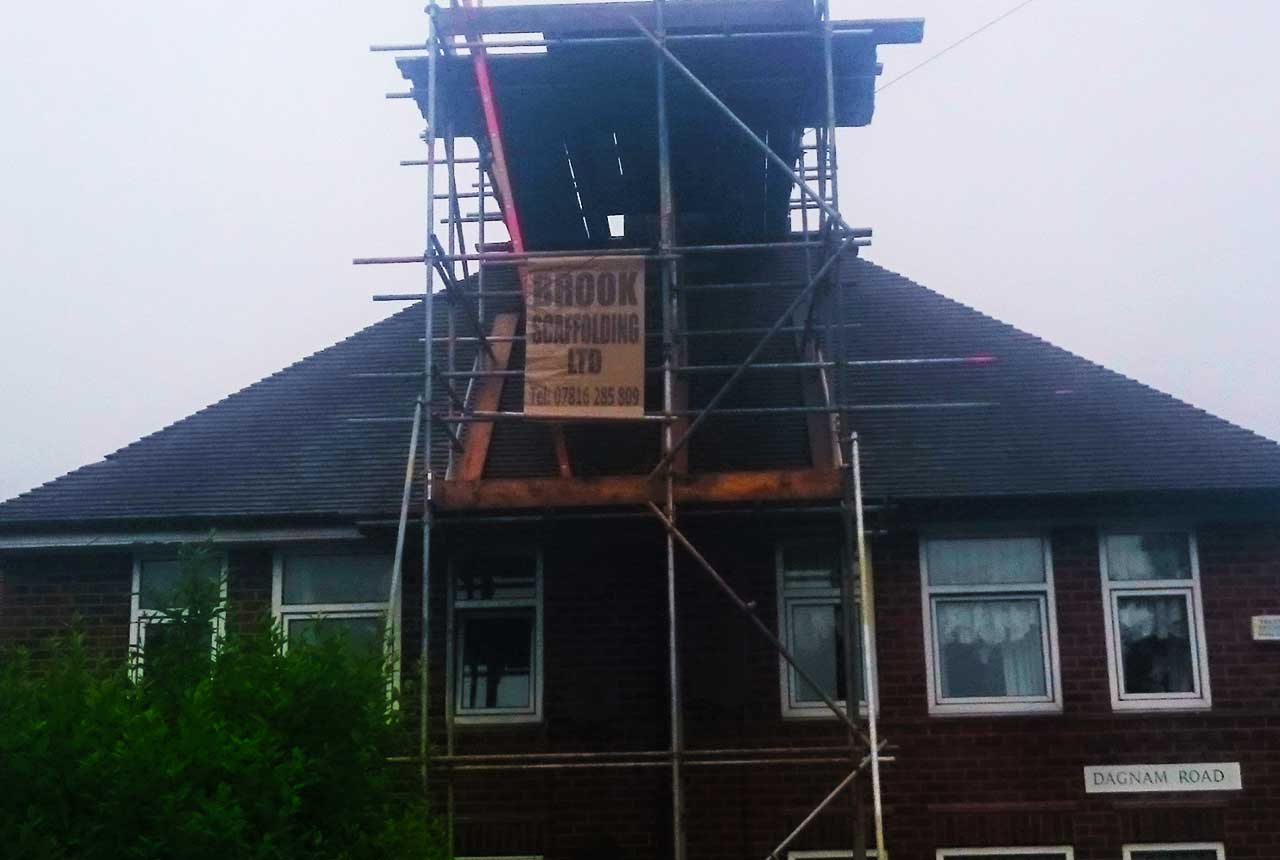 close up of a home with workmen repairing the old leaking roof on our scaffolding system erected and installed previously by us