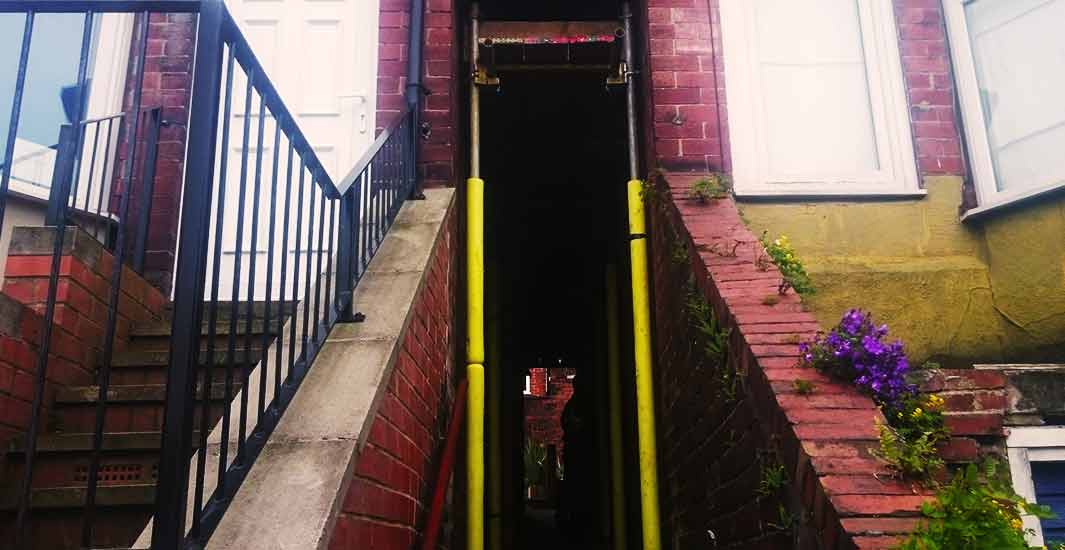 distance view of a sheffield home with adjoining alley with next door being completely supported by internal scaffolding whilst providing full access for both properties