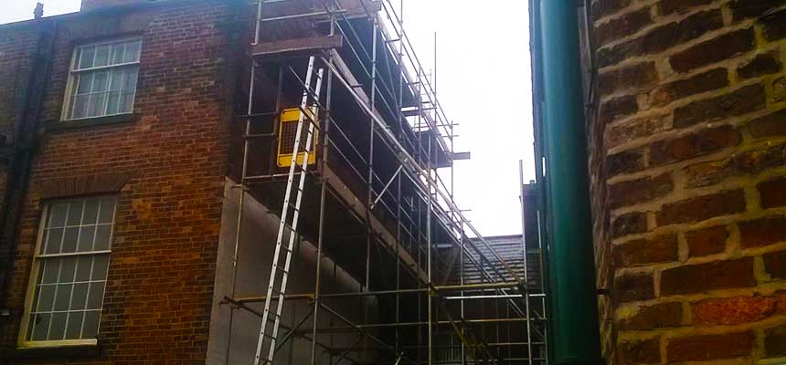 difficult ally way scaffolding allowing workers access to the hight exterior whilst allowing workers to get access to the building entrance and car park